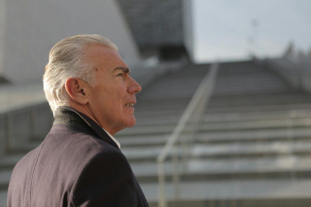 Senior man in formal attire outdoors, contemplating success in an urban setting.